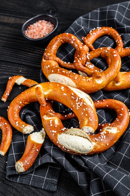 Duits gebakken gezouten pretzels op een houten rustieke tafel. zwarte houten achtergrond. bovenaanzicht.