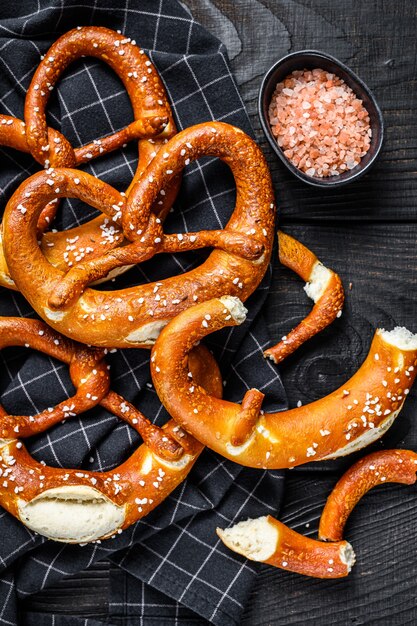 Duits gebakken gezouten pretzels op een rustieke houten tafel. Zwarte houten achtergrond. Bovenaanzicht.