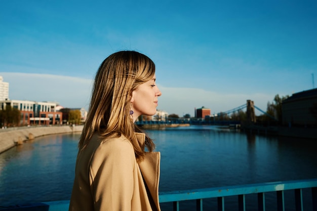 Duizendjarige blanke vrouw die aan de rivier staat en geniet van een zonnige dag