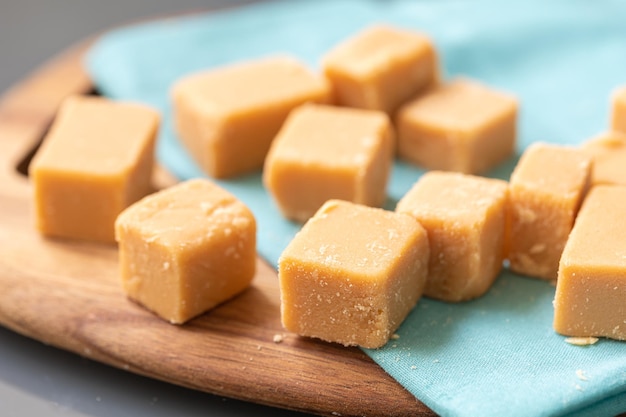 Dulce de leche in cubes on a wooden board with a napkin in the composition of the image