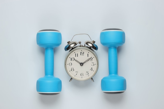 Dumbbell, alarm clock on white