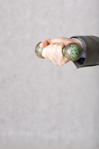 A dumbbell in the hand of a man in a classical costume. Closeup