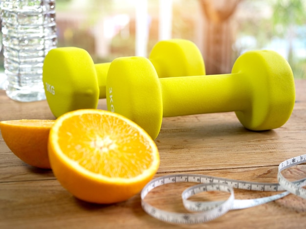 Гантель, апельсин, бутылка воды и измерительная лента для концепции фитнеса.