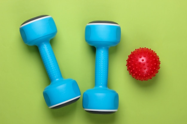 Dumbbell with massage ball on green. Fitness, healthy lifestyle concept