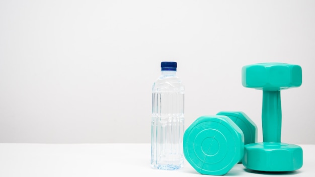 Dumbbell with water bottle on the table white background copy space