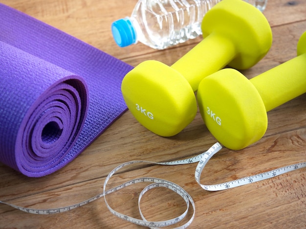 Dumbbell, yoga mat, bottle of water and measuring tape for fitness concept