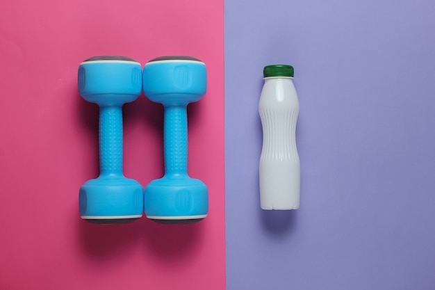 Dumbbells, a bottle of kefir on pastel paper