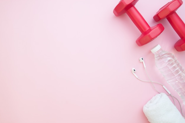 Dumbbells, bottle water on pink color background 