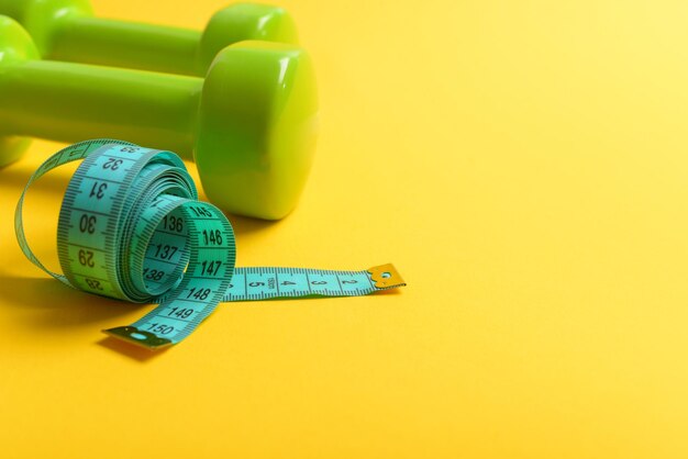 Dumbbells in bright green color isolated on yellow background