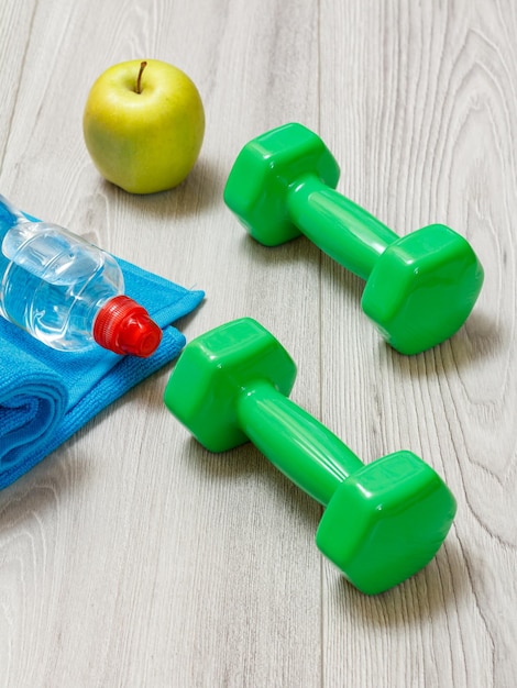 Dumbbells and different tools for fitness on floor in room