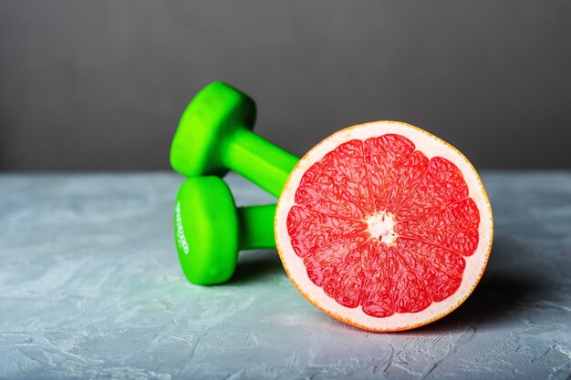 Dumbbells and grapefruit on white background. Fitness and healthy food lifestyle concept.