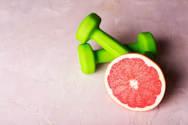 Dumbbells and grapefruit on white background. Fitness and healthy food lifestyle concept.