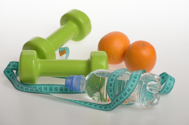 Dumbbells in green color water bottle measure tape and fruit