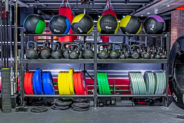 Dumbbells, pancakes and weights, leather fitballs lying on the shelves. Gym. Equipment for gym