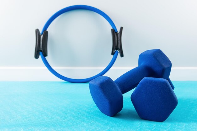 Dumbbells and a ring for sports on a blue mat