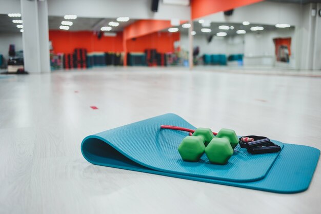 Dumbbells and sports mat in gym room