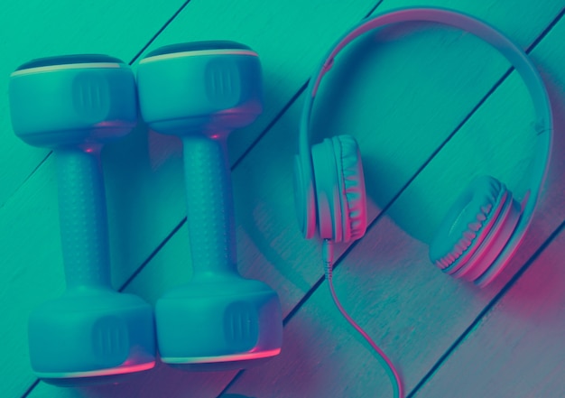 Dumbbells with headphones on wooden background