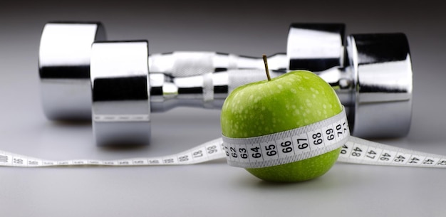 写真 背景のダイエットコンセプトのための巻尺とリンゴのダンベル
