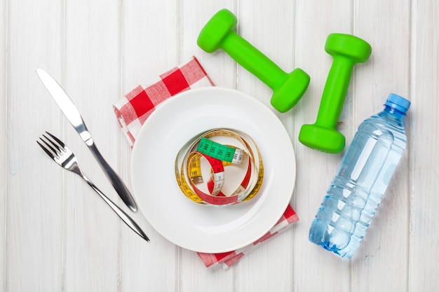 Dumbells and healthy food over wooden background. View from above