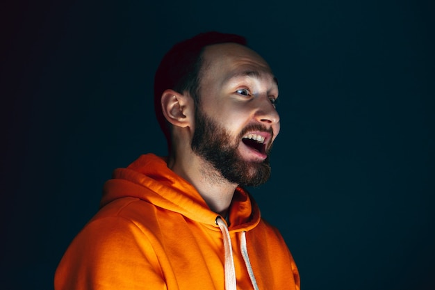 Dumbfounded. portrait of crazy scared and shocked caucasian man
isolated on dark background. copyspace for ad. bright facial
expression, human emotions concept. watching horror on tv,
cinema.