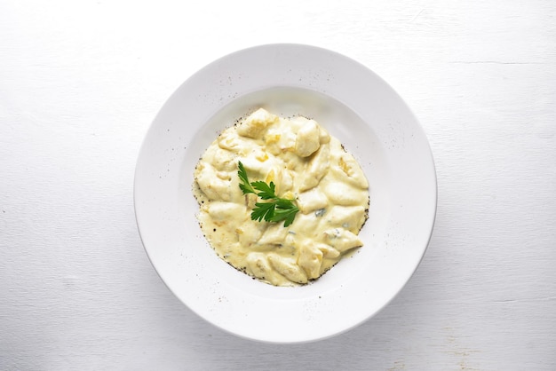 Dumpling from potatoes under cheese sauce On a wooden background Top view Free space