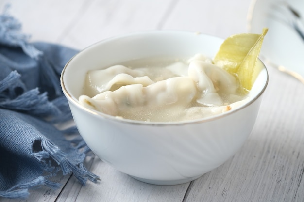 Dumpling soup in a bowl on table