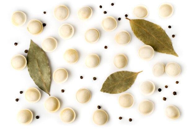 Dumplings, Bay leaf and black peppercorns on white surface