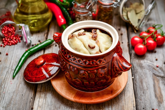 Dumplings met vlees en aardappelen in een aarden pot