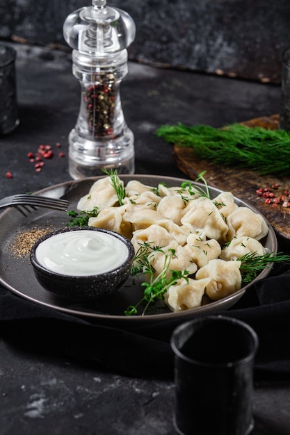 Dumplings met zure room en kruiden op een donkere plaat Vleesbollen