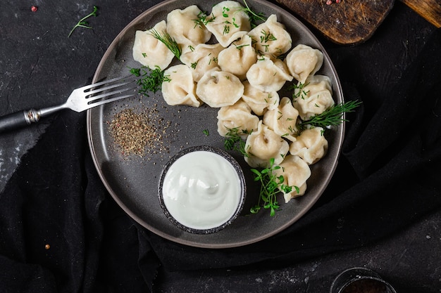 Dumplings met zure room en kruiden op een donkere plaat Vleesbollen