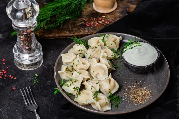 Dumplings met zure room en kruiden op een donkere plaat Vleesbollen