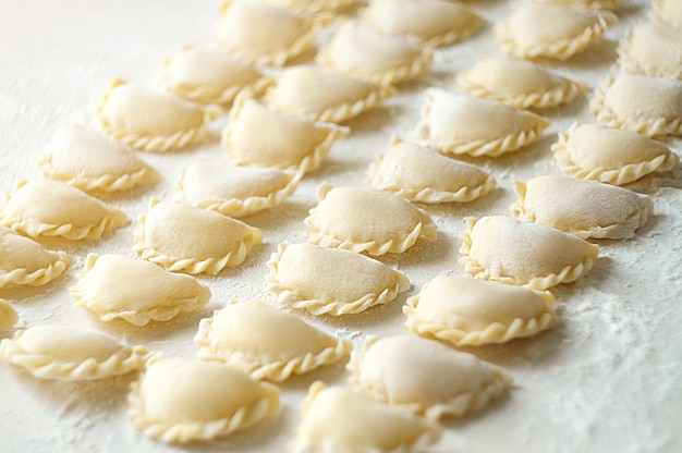 Dumplings (vareniki) with potatoes - traditional Ukrainian food. Cooking raw dumplings with potatoes