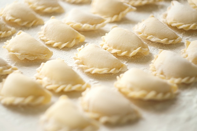 Dumplings (vareniki) with potatoes - traditional Ukrainian food. Cooking raw dumplings with potatoes