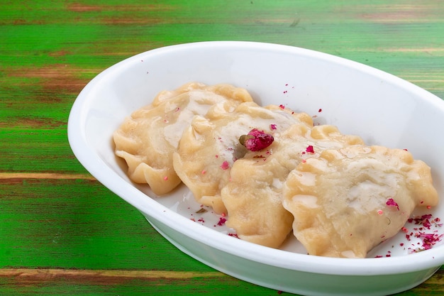 Dumplings with cherries On a colored wooden background Vegetarian dish