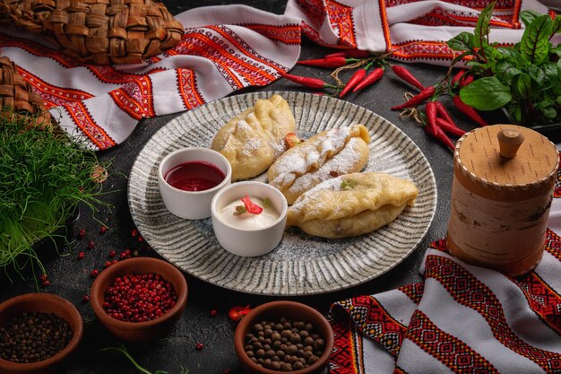 Photo dumplings with cherries in a gray plate on a dark background with jam and sour cream