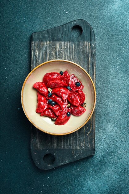 Photo dumplings with cherries raspberries and salted caramel on a black stone background in a plate closeup