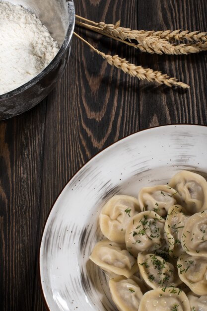 Dumplings with meat. Russian national dish on a white plate. Wooden board