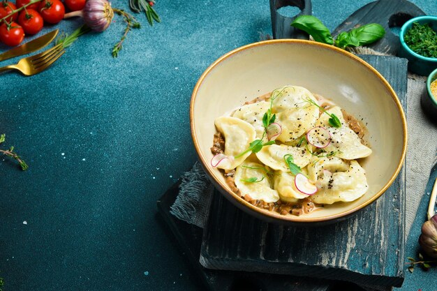 Dumplings with potatoes and mushroom sauce On a black stone background In a plate closeup