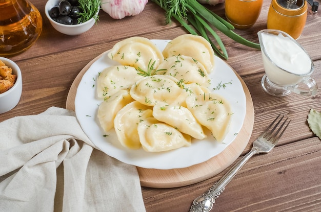 Dumplings with potatoes on a white plate on a dark wooden background