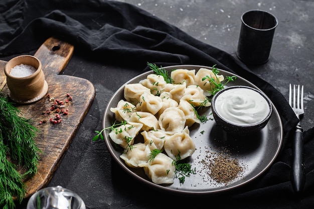 Dumplings with sour cream and herbs on a dark plate Meat dumplings