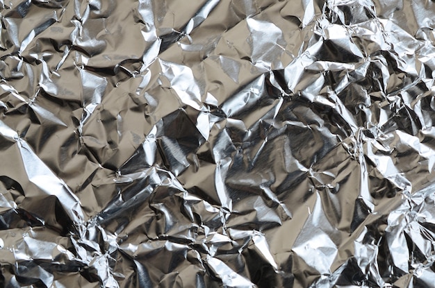 Dun, gerimpeld vel geplette aluminium aluminiumfolie achtergrond met glanzend verfrommeld oppervlak voor textuur