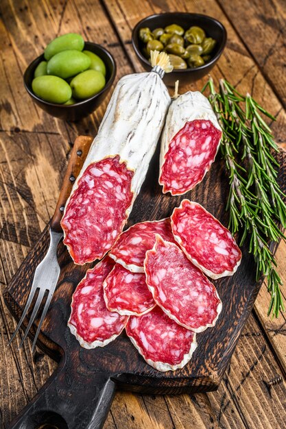 Dun gesneden salami salchichon op een houten snijplank. houten achtergrond. Bovenaanzicht.