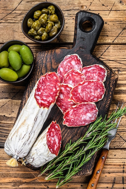 Dun gesneden salami salchichon op een houten snijplank. houten achtergrond. Bovenaanzicht.