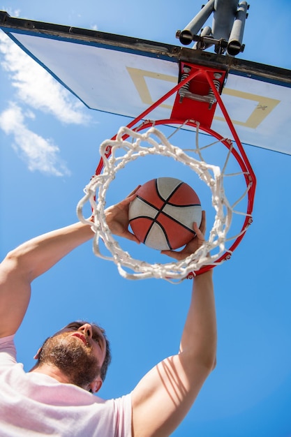 Dunk in basket slam dunk in beweging zomer activiteit energieke man met basketbal bal op het veld professionele basketbalspeler training buiten man heeft sport motivatie sport en hobby