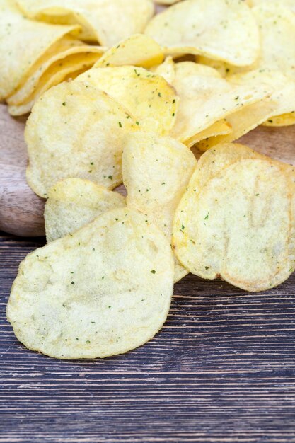 Dunne chips met kruiden en zout, chips gebakken in olie en besprenkeld met kruiden, schadelijk fastfood