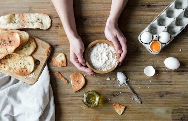 Dunne italiaanse flatbread met kruiden. dunne tortilla's, traditionele italiaanse focaccia met olijfolie en zout. kookproces met ingrediënten met handen.