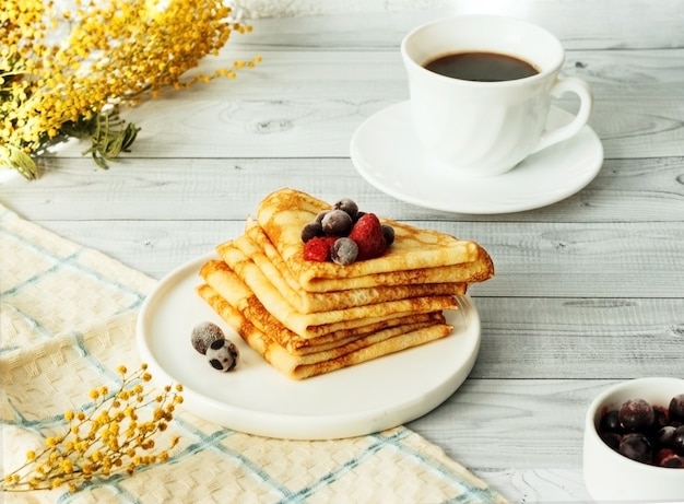 Dunne pannenkoeken met framboos en bes op plaat. Russisch traditioneel dessert voor vastenviering (maslenitsa).