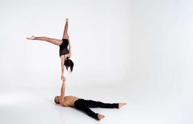 Duo of male and female acrobats showing hand to hand trick,\
isolated on white