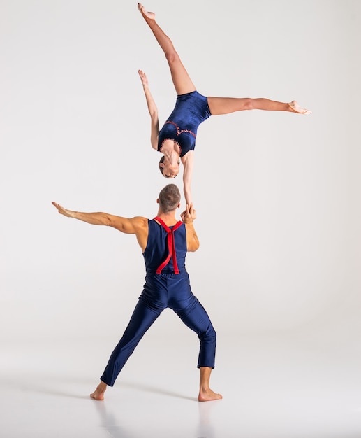 Duo of male and female acrobats showing hand to hand trick,\
isolated on white