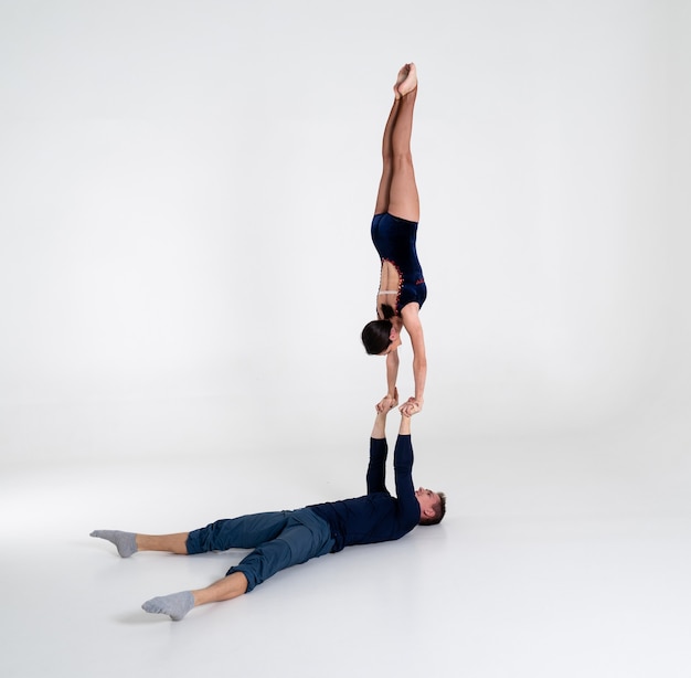 Photo duo of male and female acrobats showing hand to hand trick, isolated on white